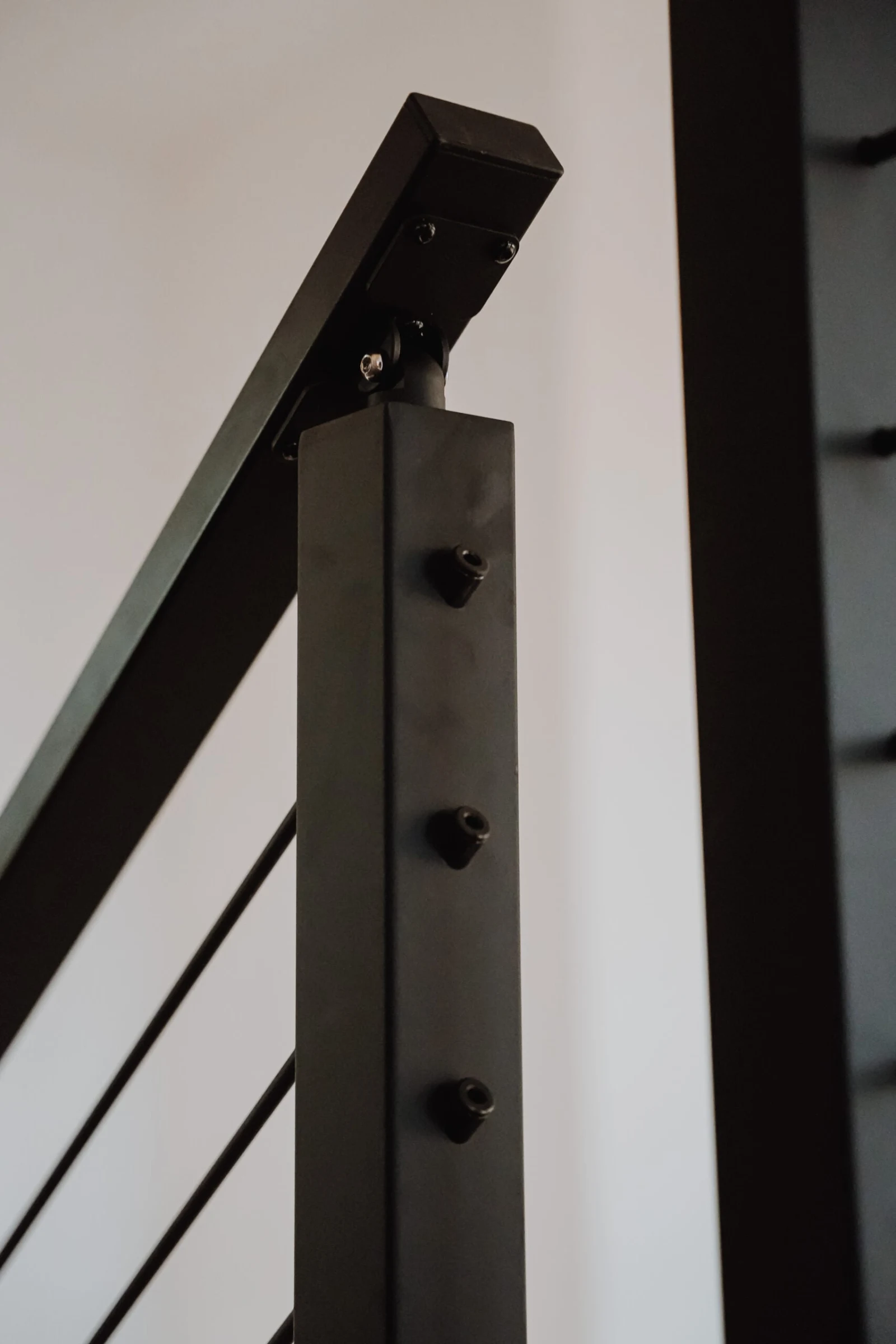 Detail of a black post with threaded rod terminations and an angled top rail