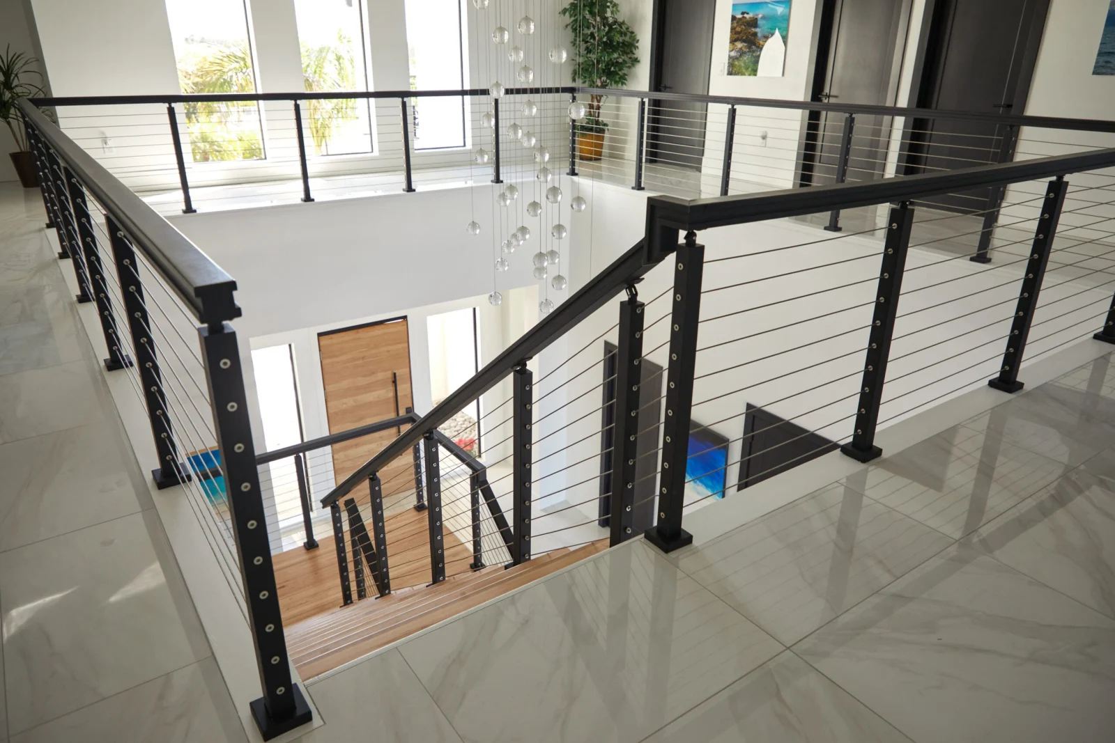 Cable railing wrapping a second-floor overlook above the stair opening on polished tile