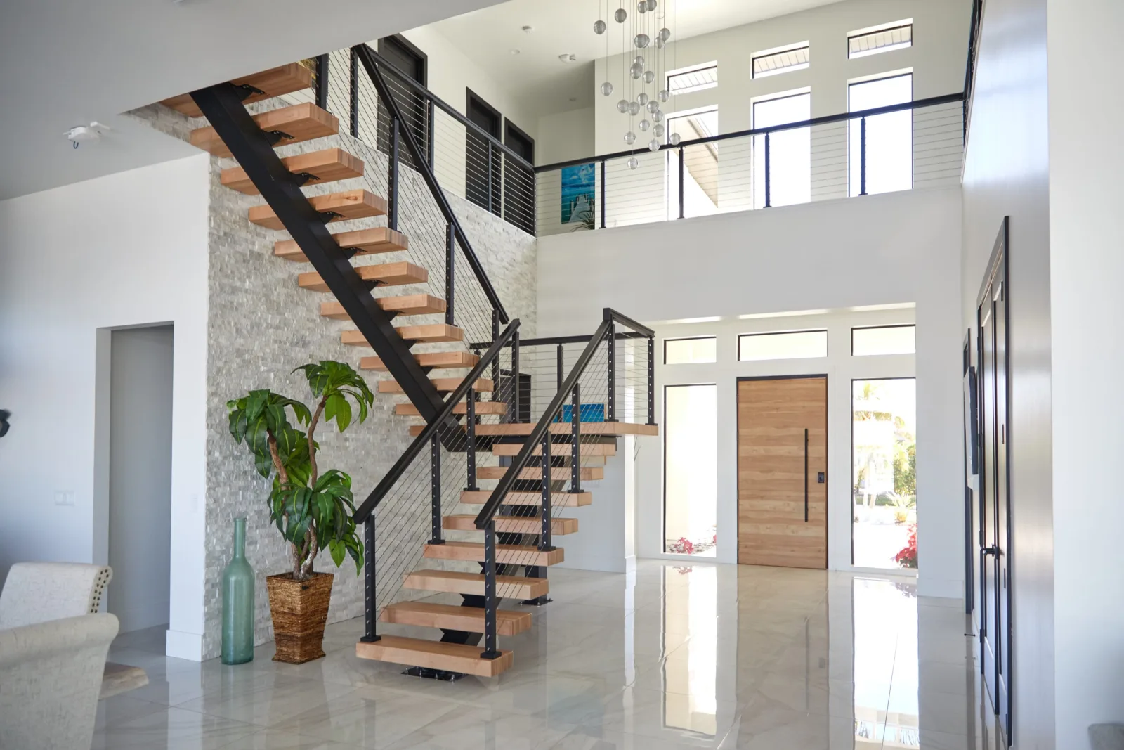 Open entry with tall transom windows, a wood front door, and the stair alongside