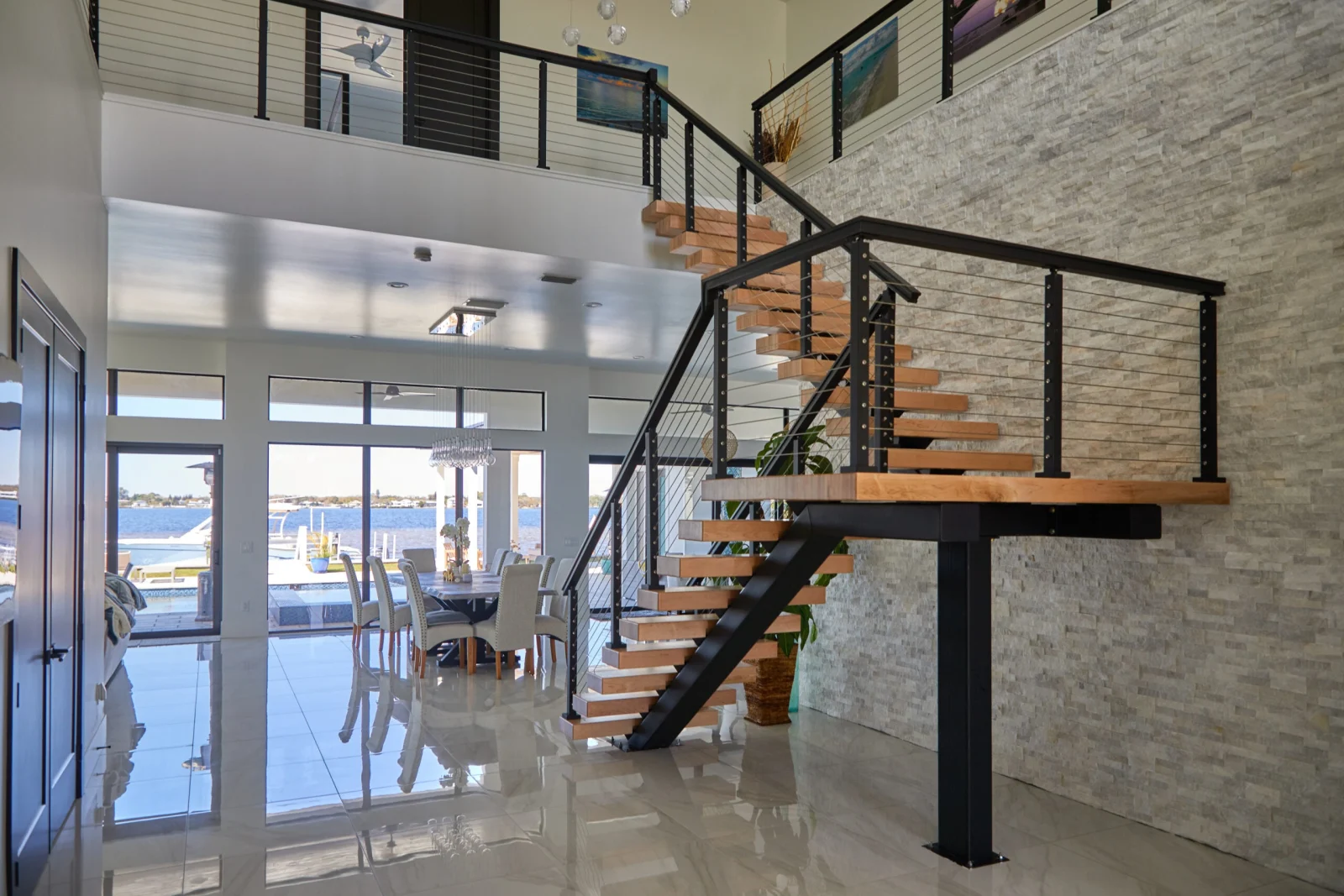 Living area with water views through sliding doors and the stair on its black stringer