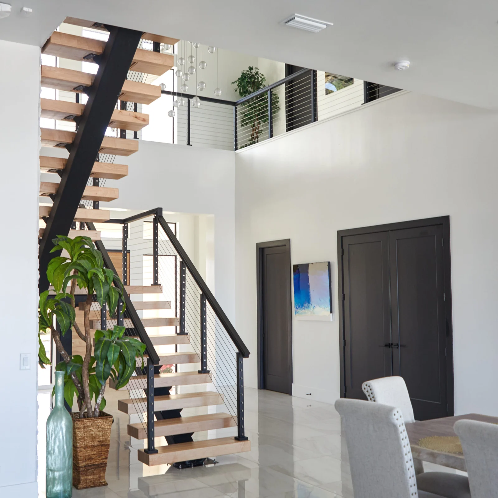 Wide room view with the floating stair turning at the corner near dark double doors