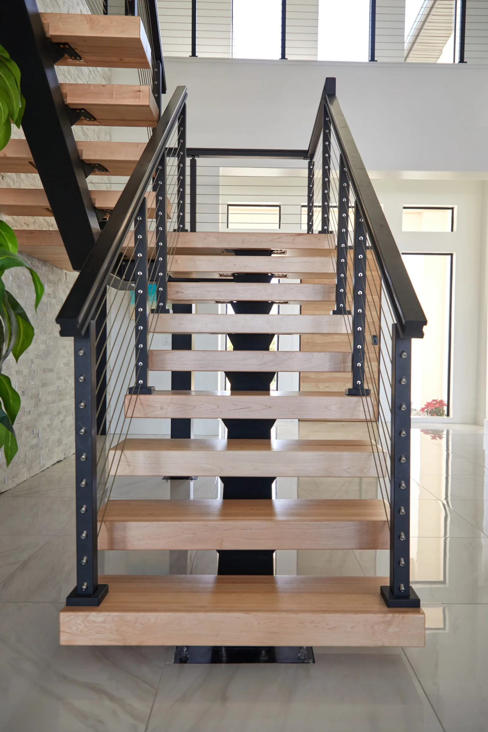 Straight-on view up the open-riser flight with cable railing on both sides