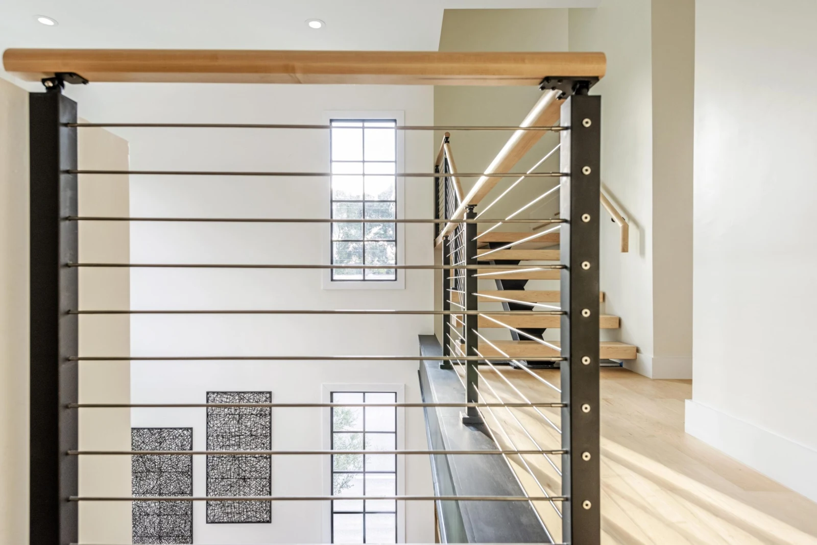 Straight run of rod railing with a rounded wood top rail near the stair landing