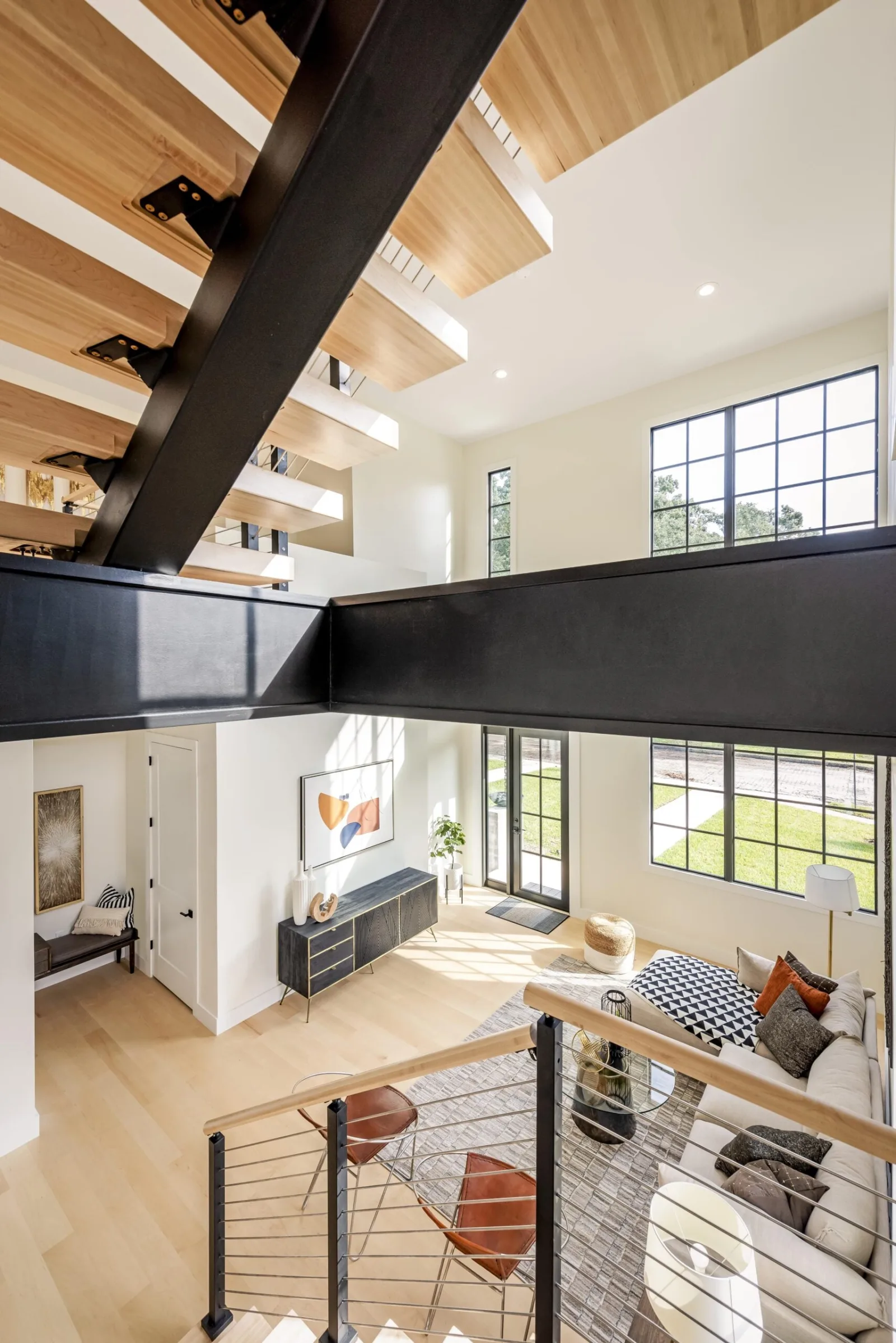 View down past the black stringer to the living room and tall windows below