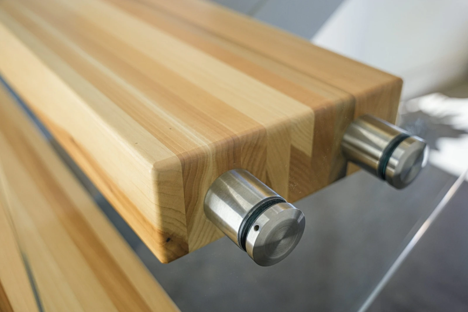 Angled close-up of a tread corner and the polished pins holding the glass railing