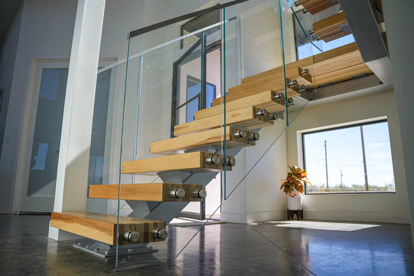 Low angle on glass panels with standoff pins wrapping pale treads over polished concrete
