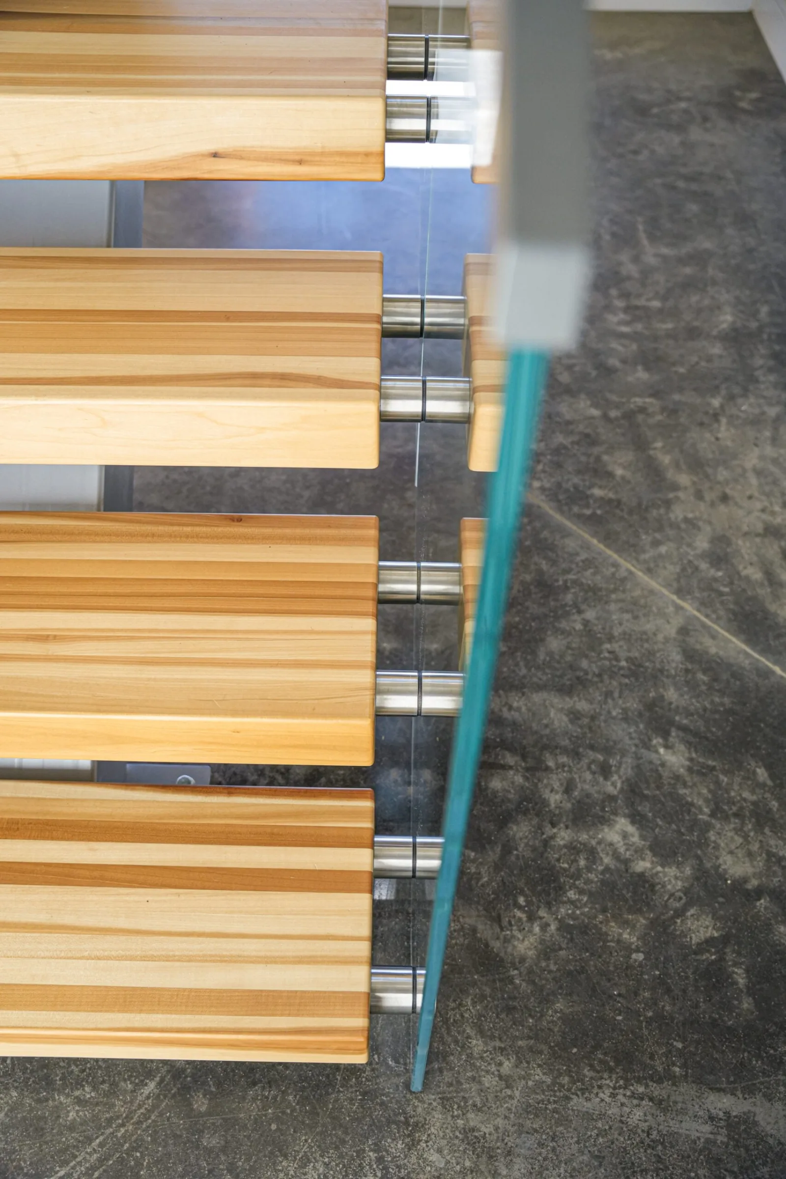 Low angle along tread ends where the glass panel meets polished concrete below