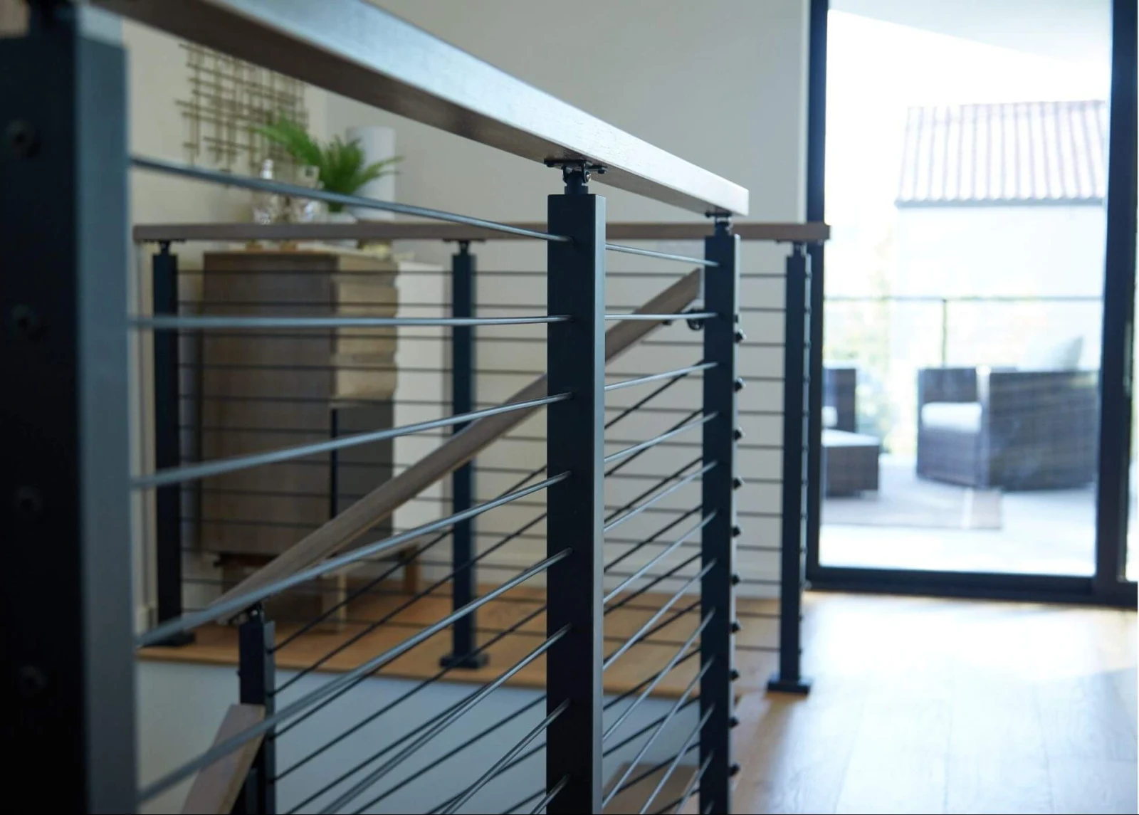 Rod railing with dark posts and a wood top rail beside a sliding patio door