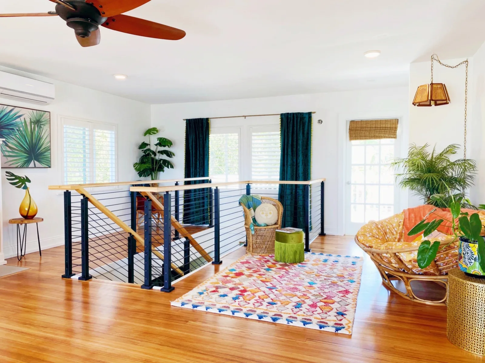 Upstairs landing where rod railing rings the stair opening under a wood ceiling fan