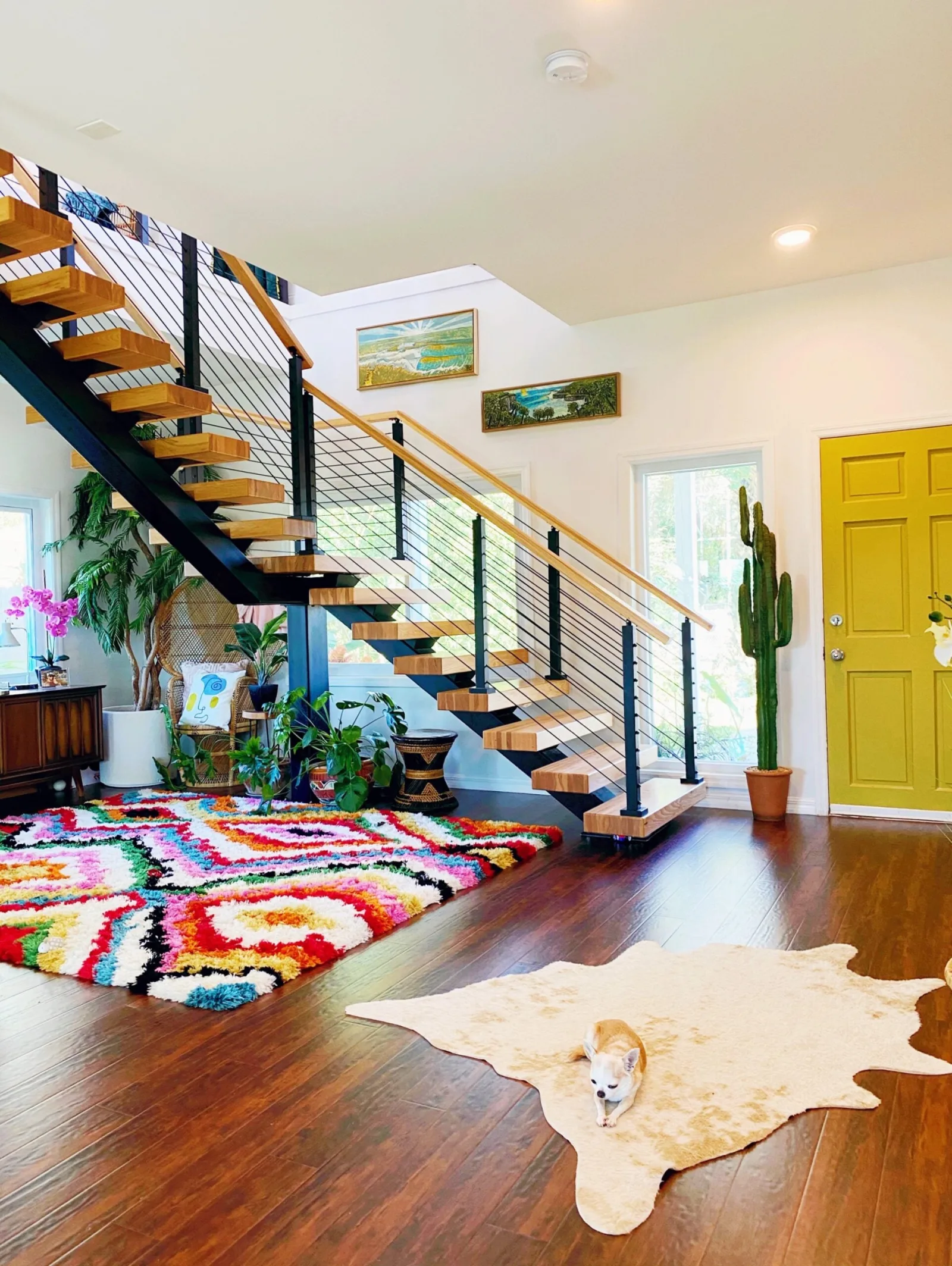 Entry stair with light treads above a bright patterned rug and yellow-green door