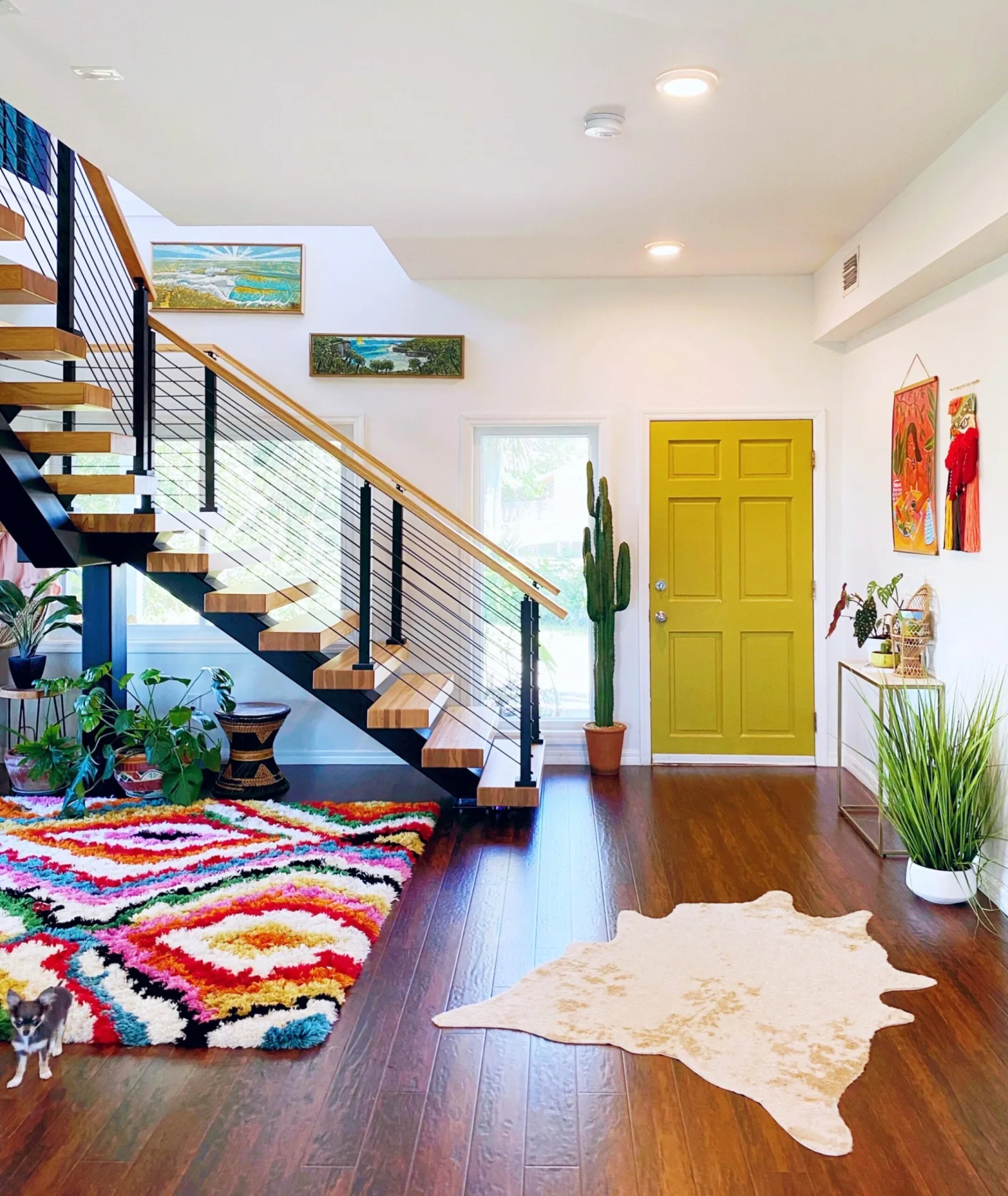 Entry hall with the floating stair, patterned rug, and a bright green front door