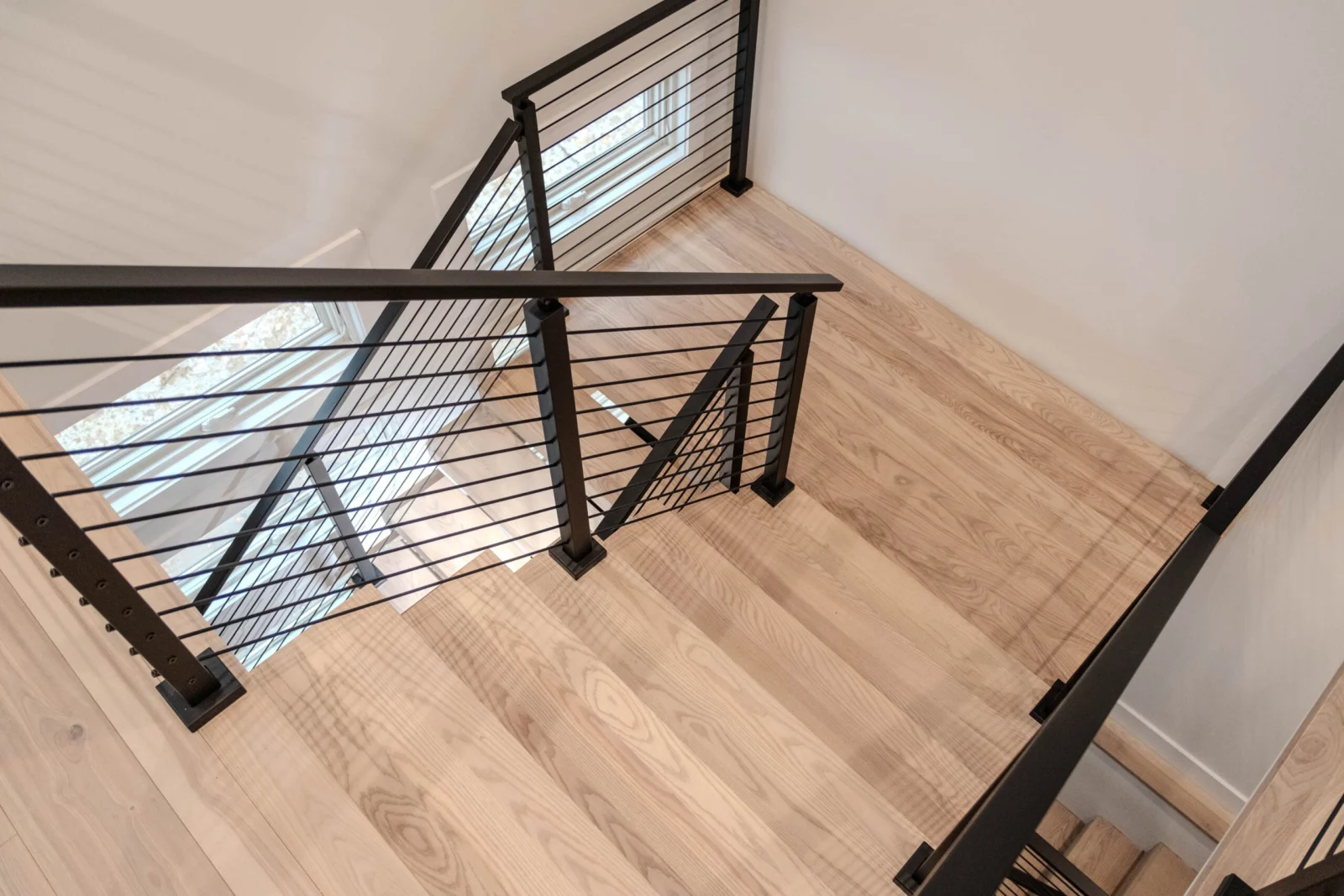 Looking down from the top landing at rod railing framing the stair opening
