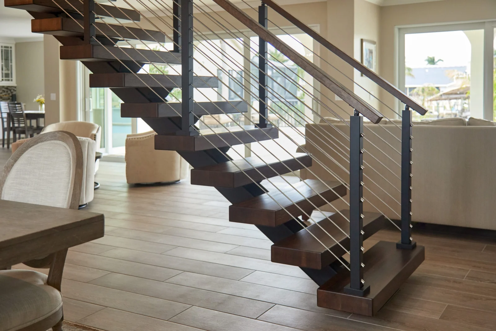 Dark wood treads and black center stringer with horizontal rod infill in an open living area