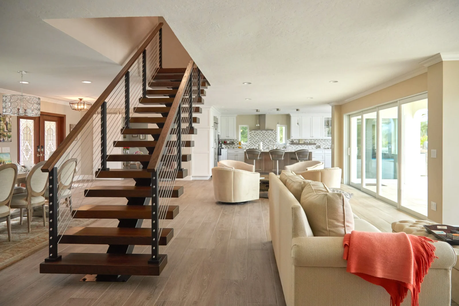 Flight rising through the great room with the kitchen and entry doors beyond