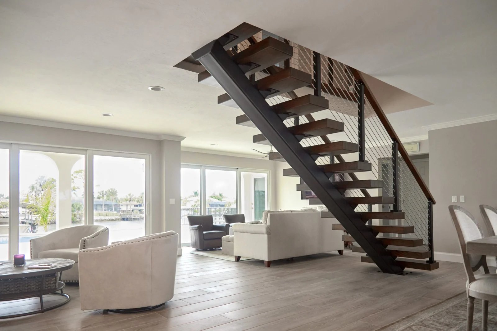 Open plan room with the floating stair on a black stringer near waterfront doors
