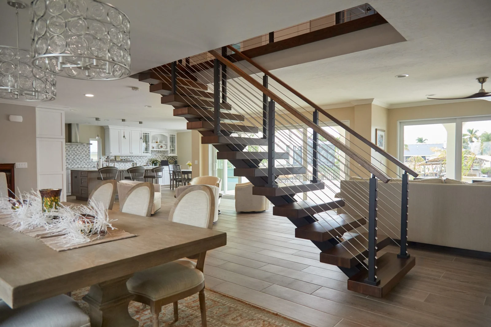 Dining table foreground with the stair and rod railing crossing the open floor plan