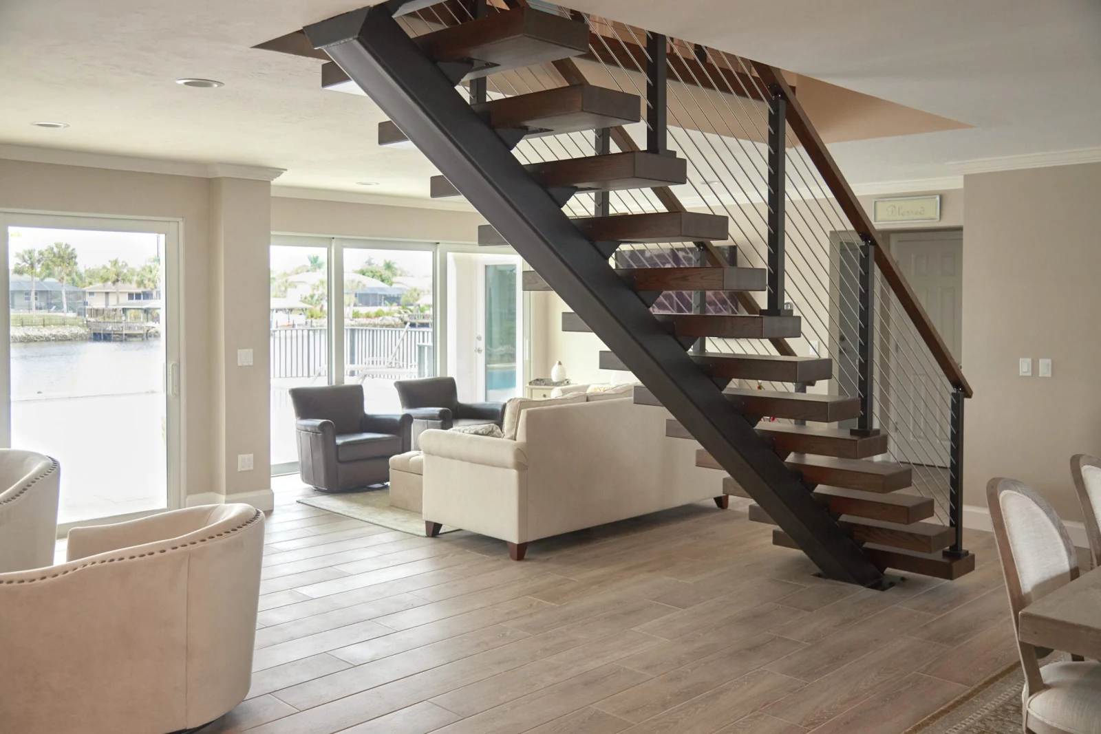Living space seen past lounge chairs to the flight and its rod railing