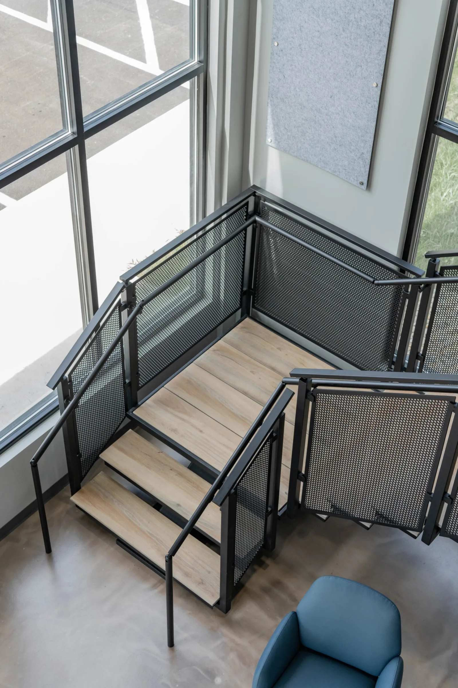 Overhead view of a switchback stair with perforated metal railing panels and pale stone treads