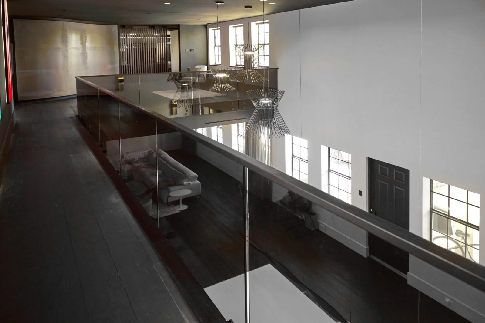 Tinted glass balcony run overlooking a dark plank floor and window wall