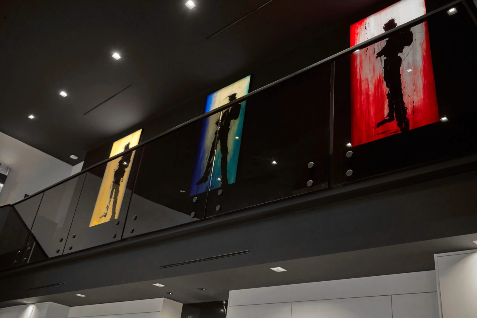 Balcony glass panels lit from below with three framed artworks above