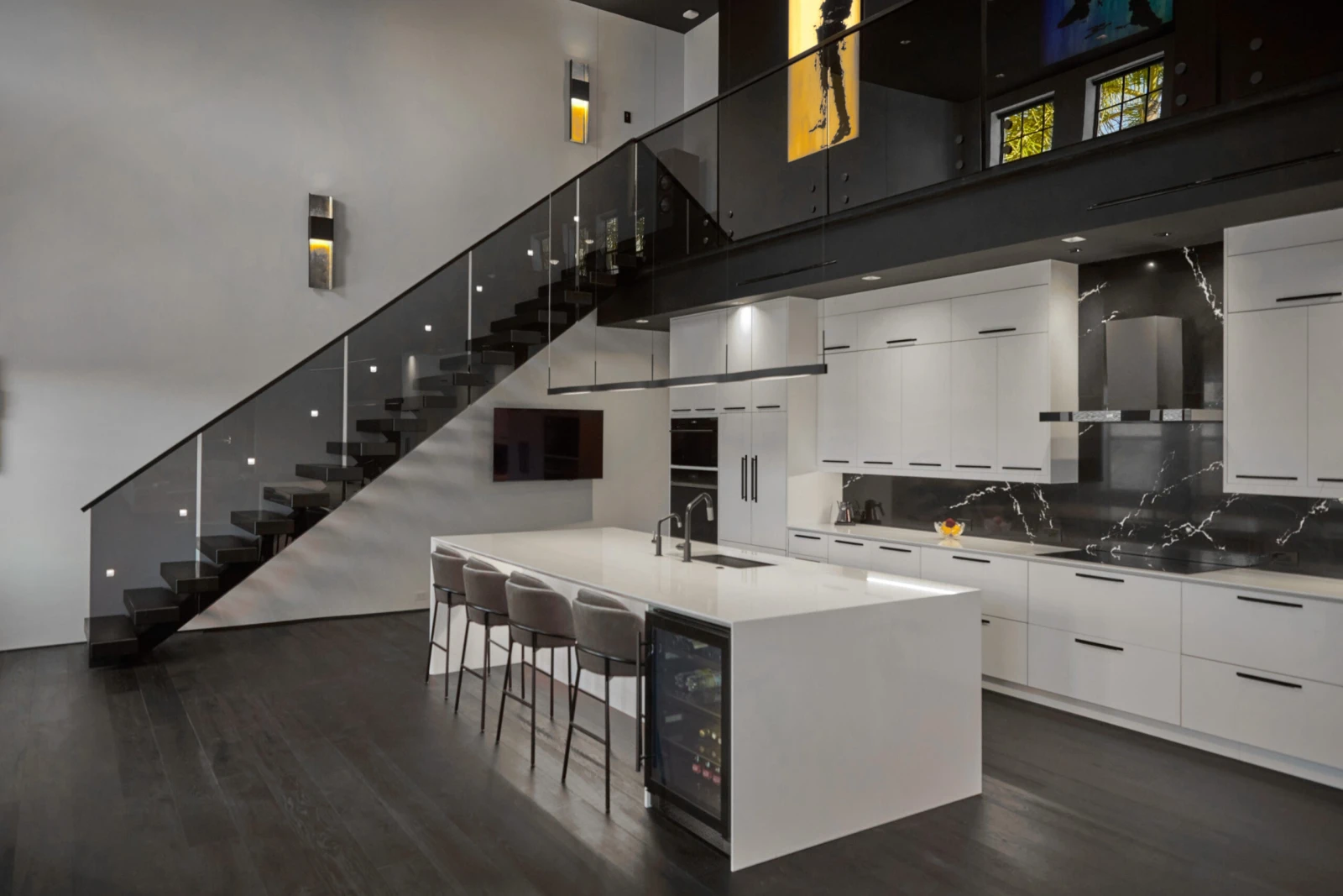 Kitchen island and the stair passing overhead behind a smoked glass railing