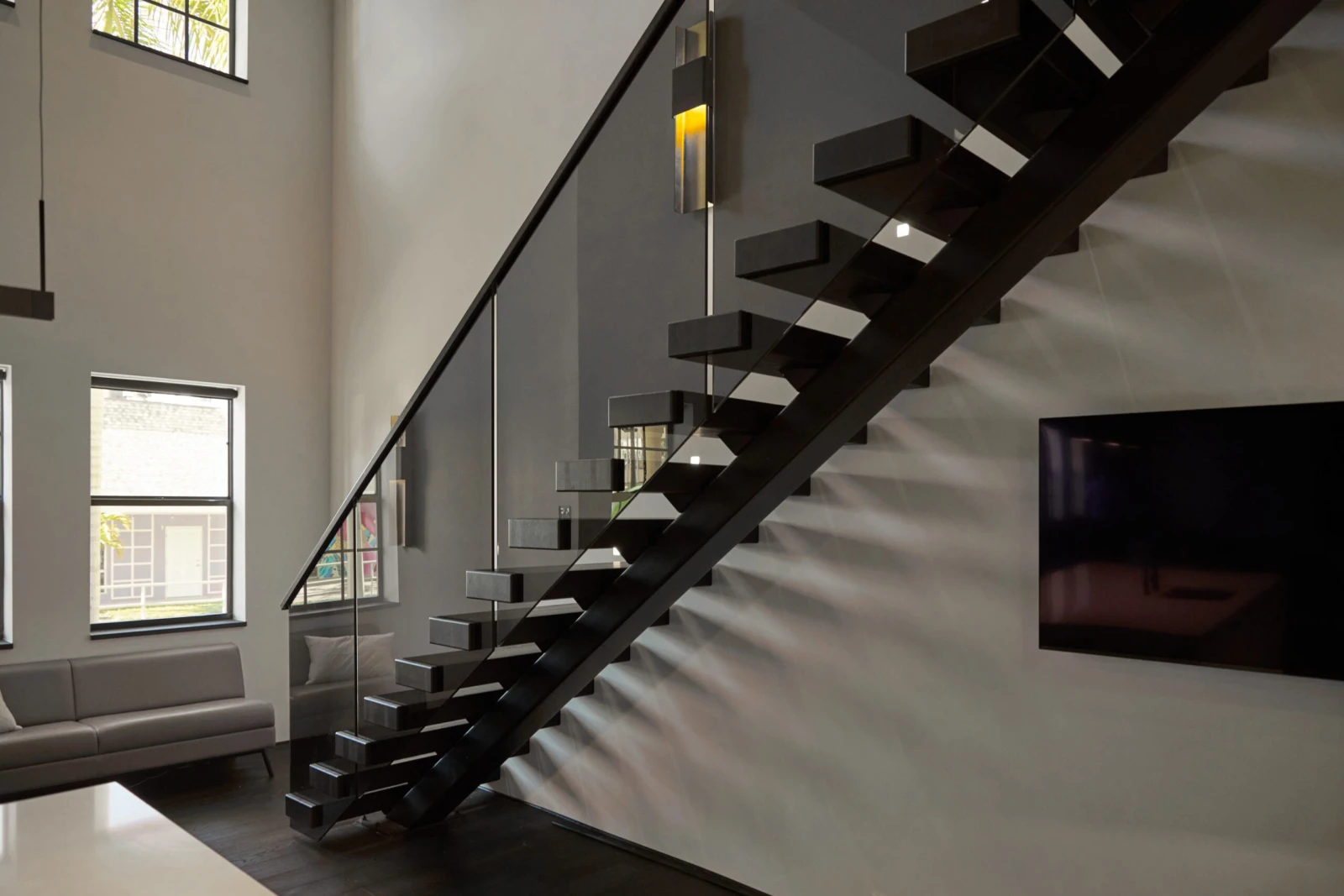 Side view of the cantilevered treads and glass panels along a textured wall