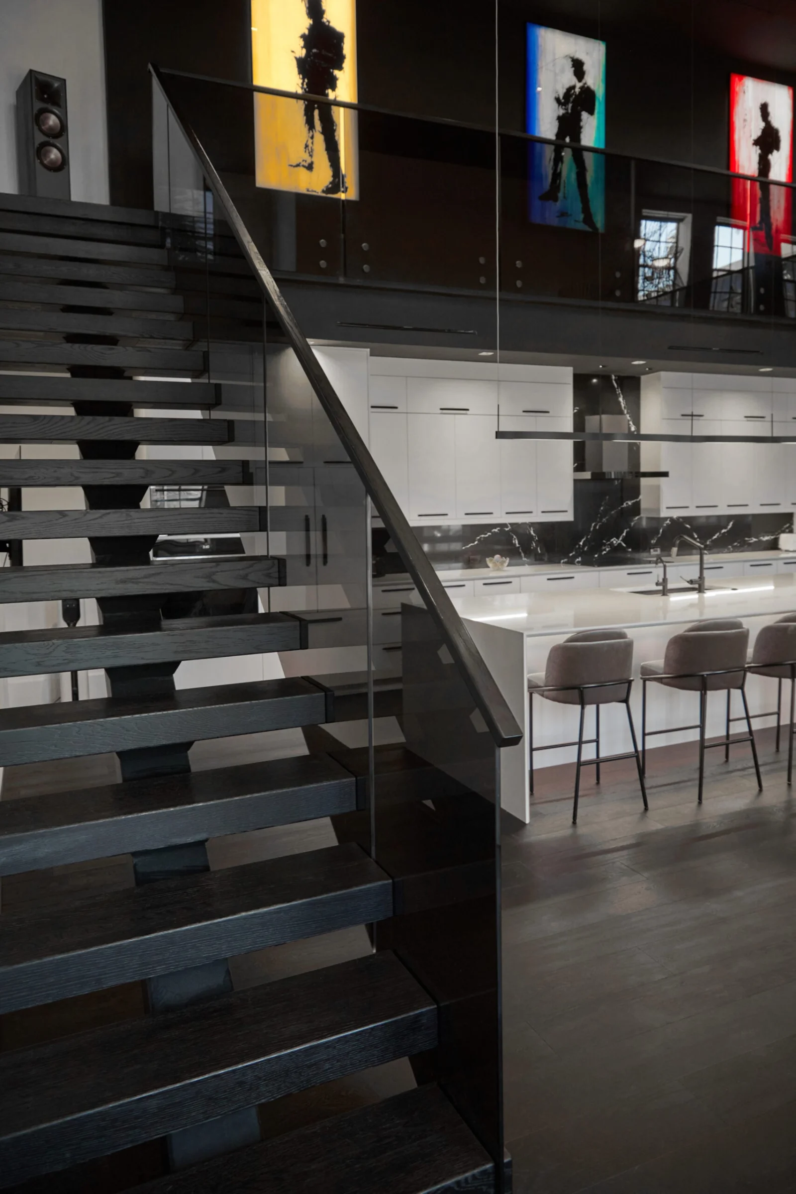 Stair edge in shadow with the bright kitchen and stools beyond the glass