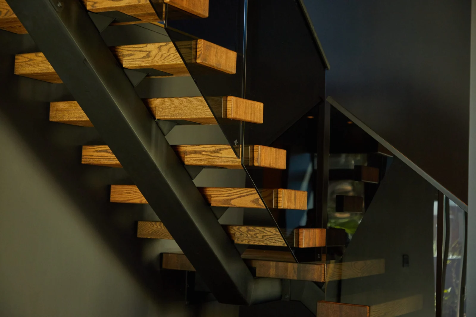 Warm light across the treads with the glass railing and dark stringer