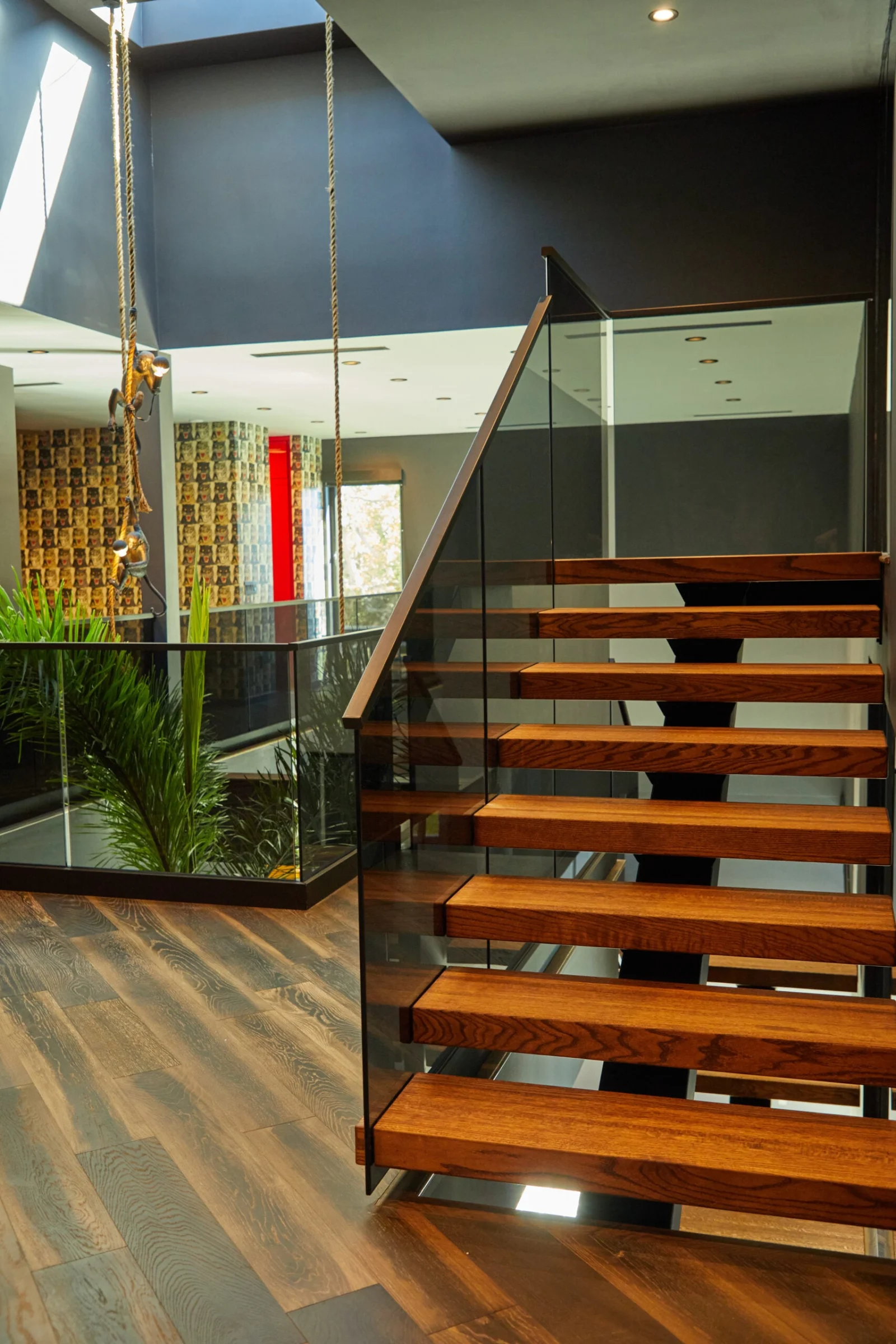 Stair and glass railing with the planted bed and lit ceiling beyond