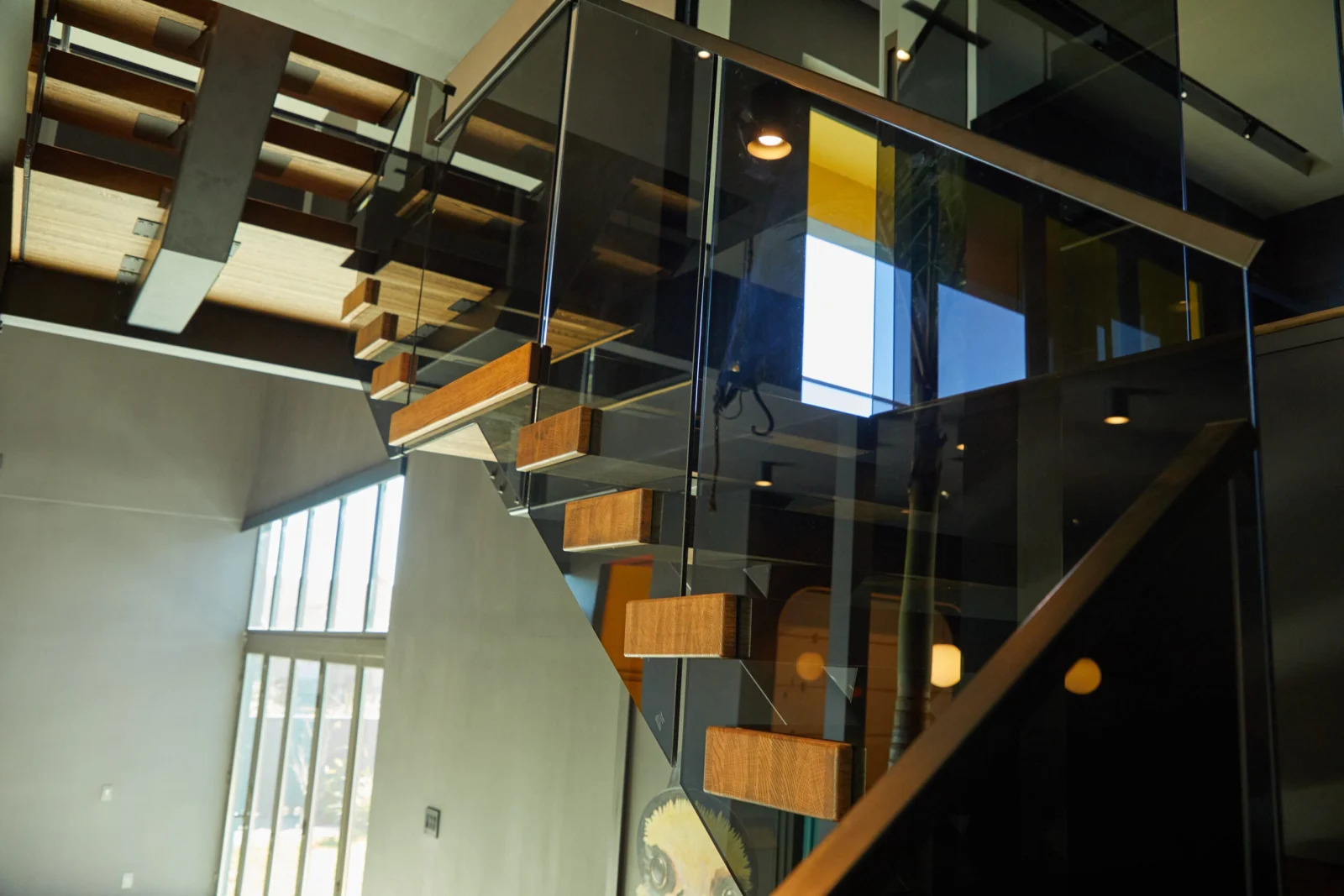 Upward view of the flight with glass panels reflecting the lit ceiling