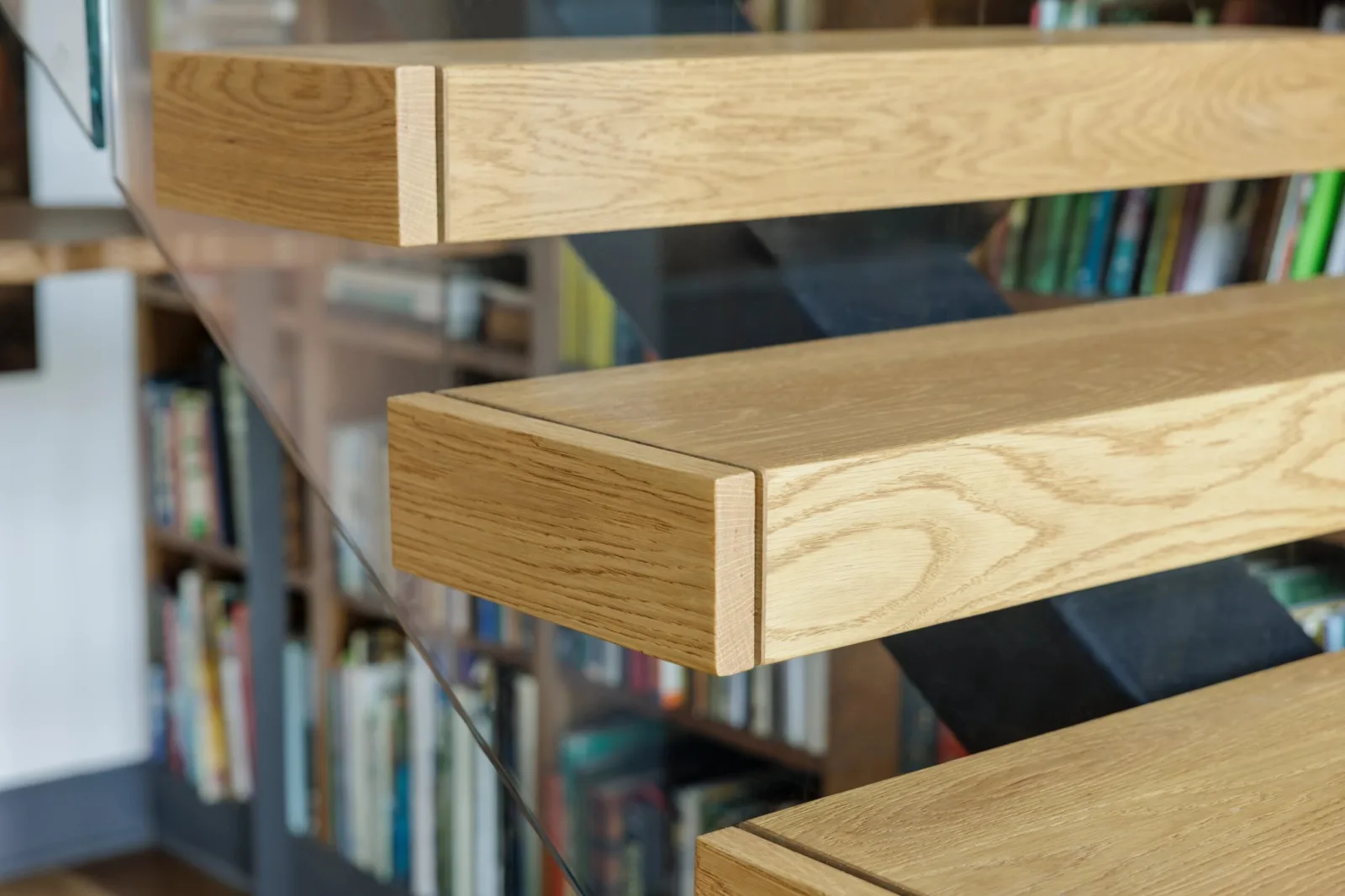 Close view of tread ends and the glass panel with book spines behind