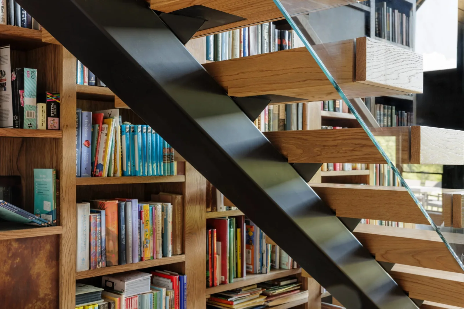 Black stringer crossing the bookshelves with treads cantilevered from it
