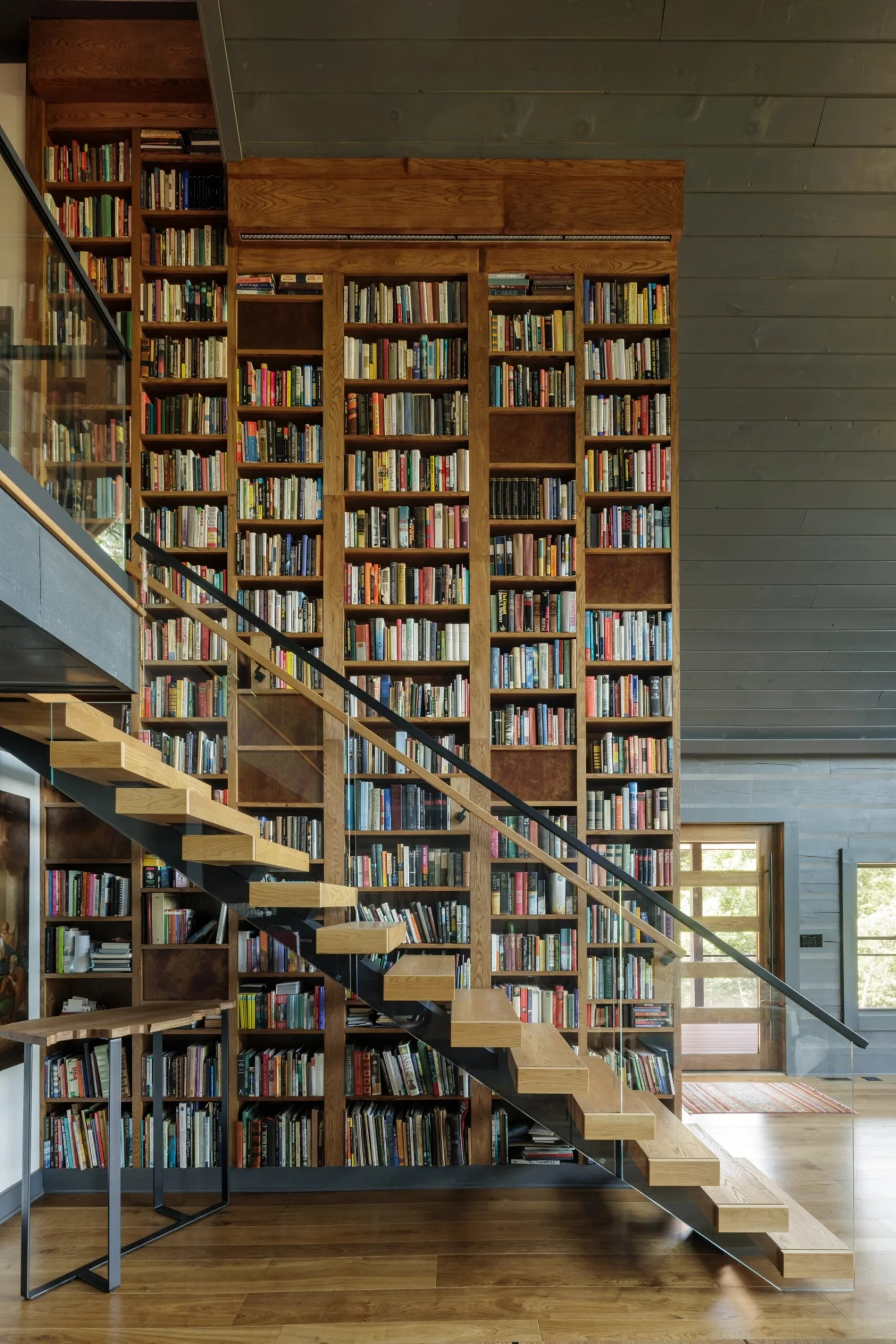 Full library wall of books behind the flight and its black handrail