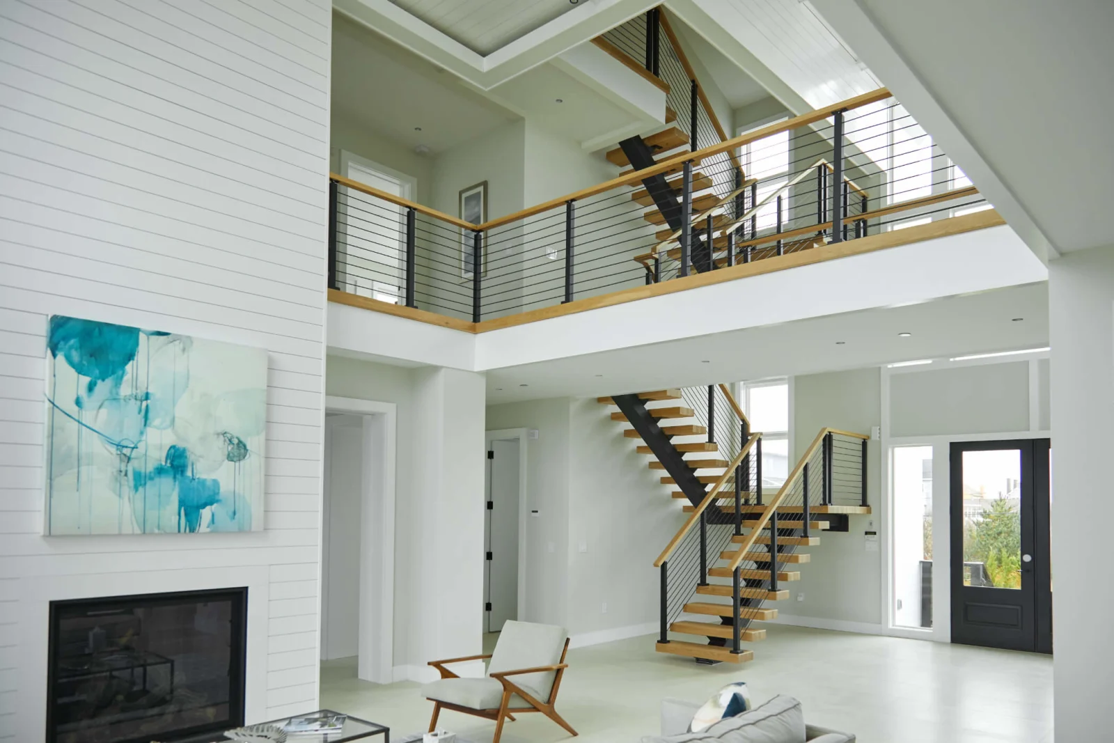 Two-story great room where a floating stair and balcony run share horizontal rod railing