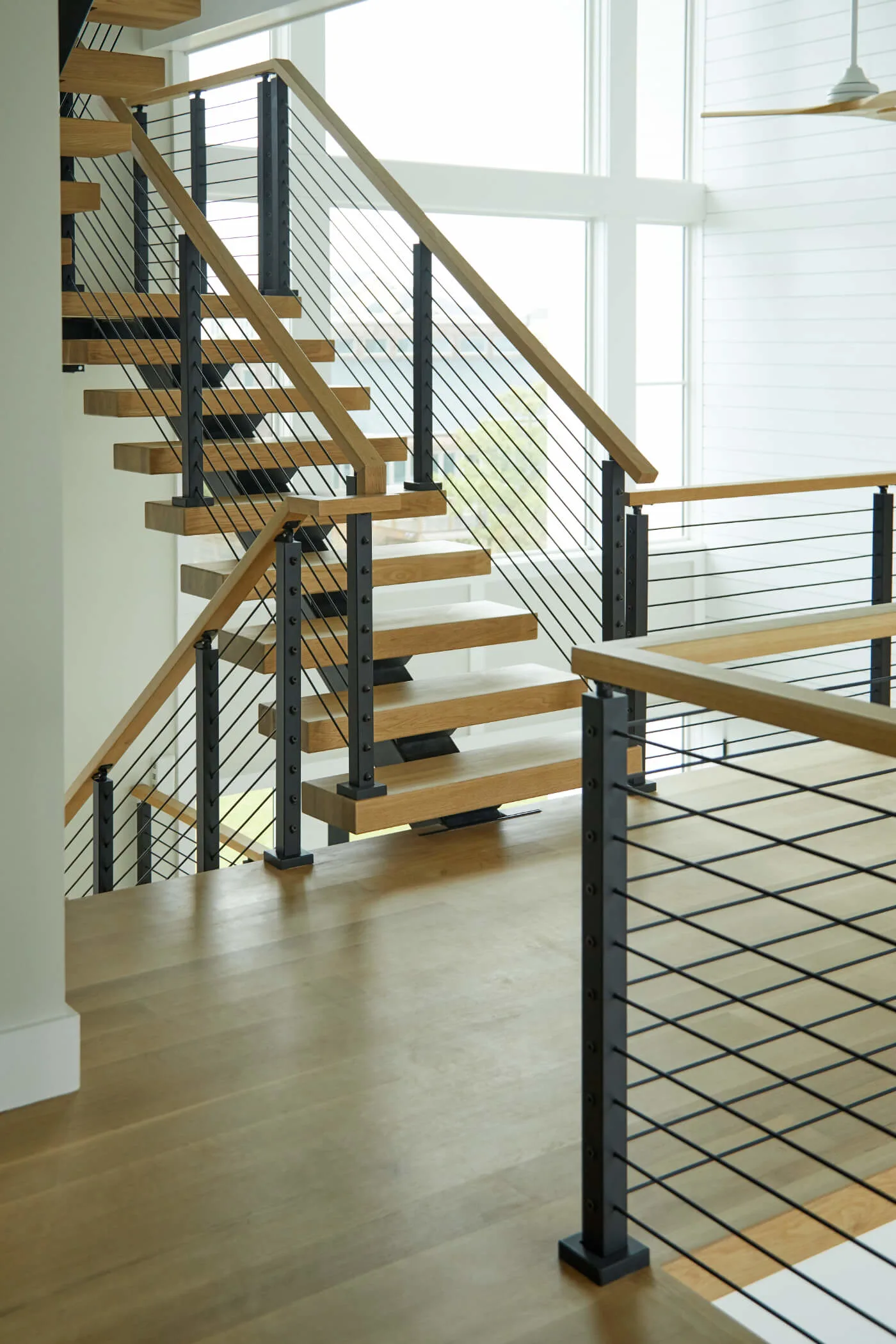 Stair run and balcony railing meeting at a black newel beside the floor