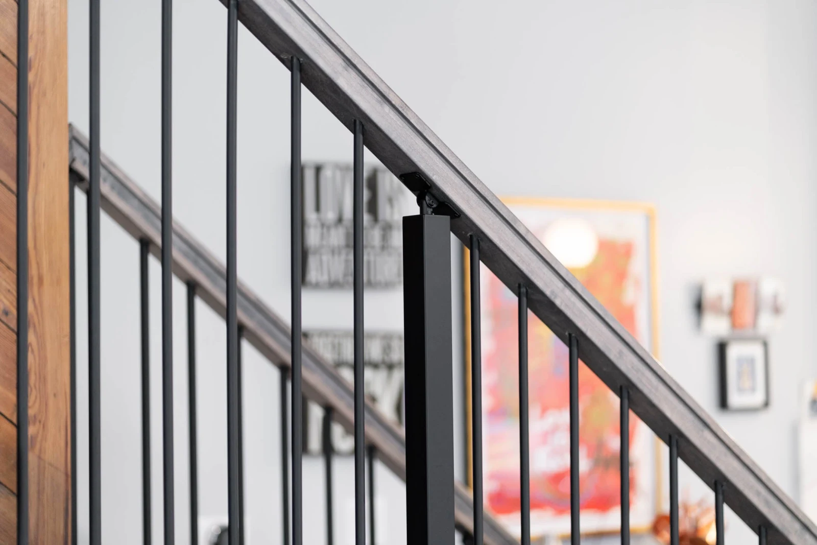 Angled rod railing against a white wall with framed art beyond