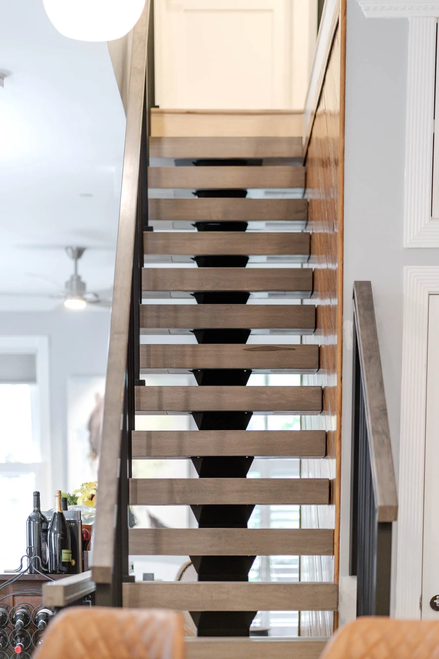Straight run of treads climbing between rod railing and white cabinetry