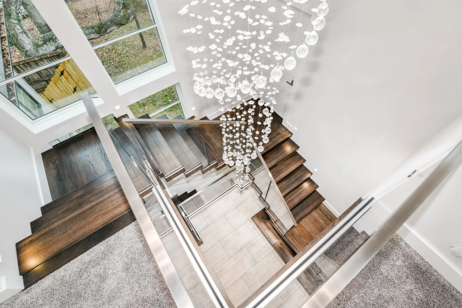 Looking down the switchback past a cascading chandelier and glass railing