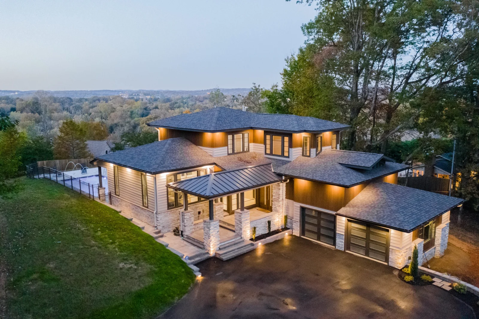 Aerial dusk view of the house with lit entry and stone drive