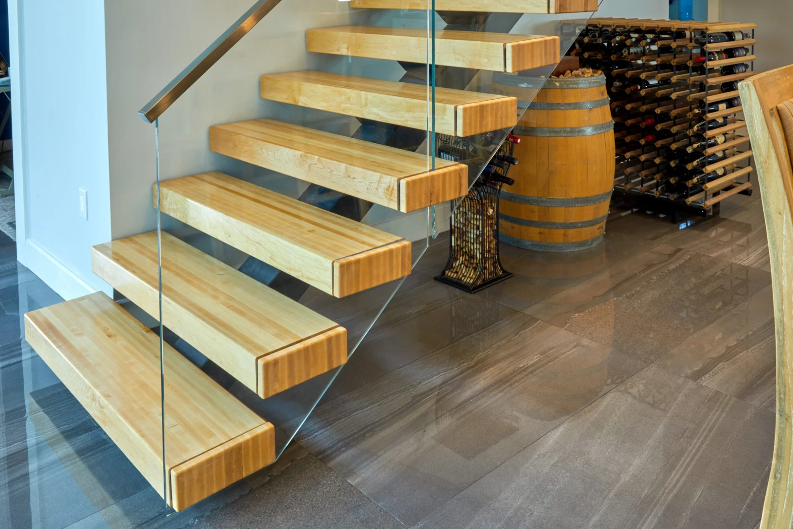 Close view of thick wood treads and glass panel above a wine barrel