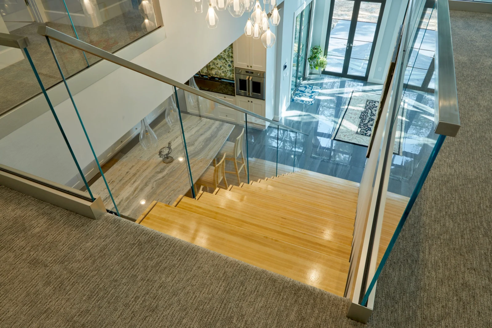 Looking down the flight from a carpeted landing lined with glass railing