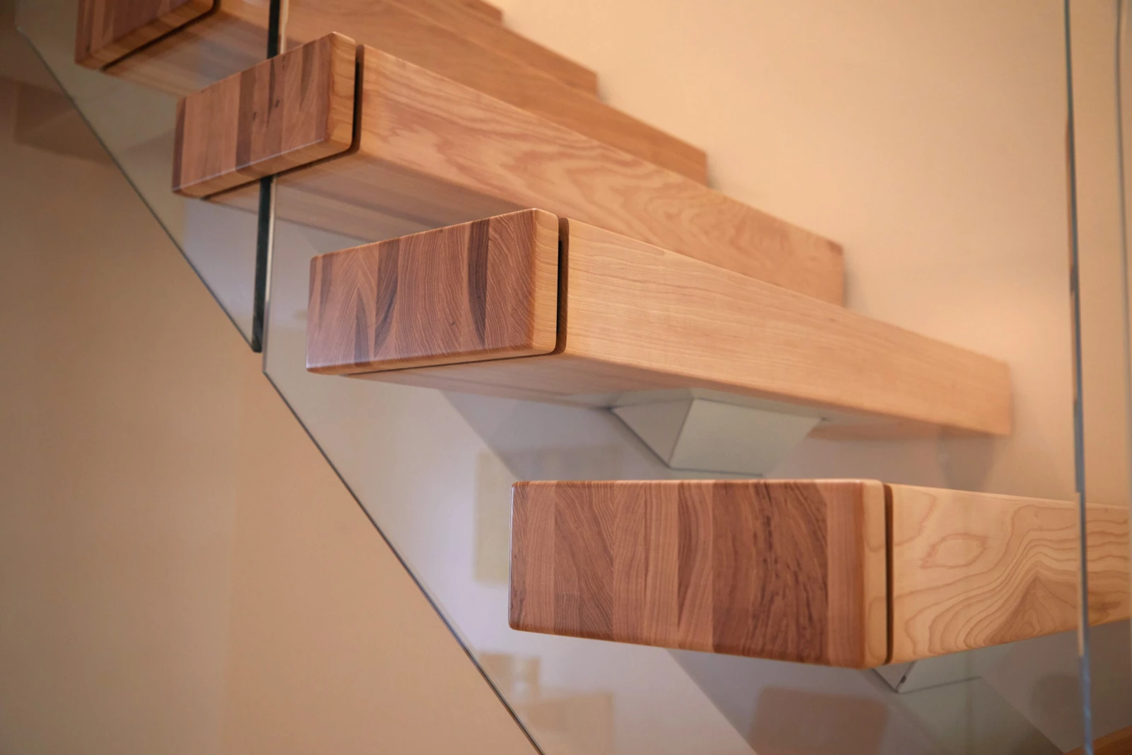 Low angle along projecting tread ends with glass railing running behind