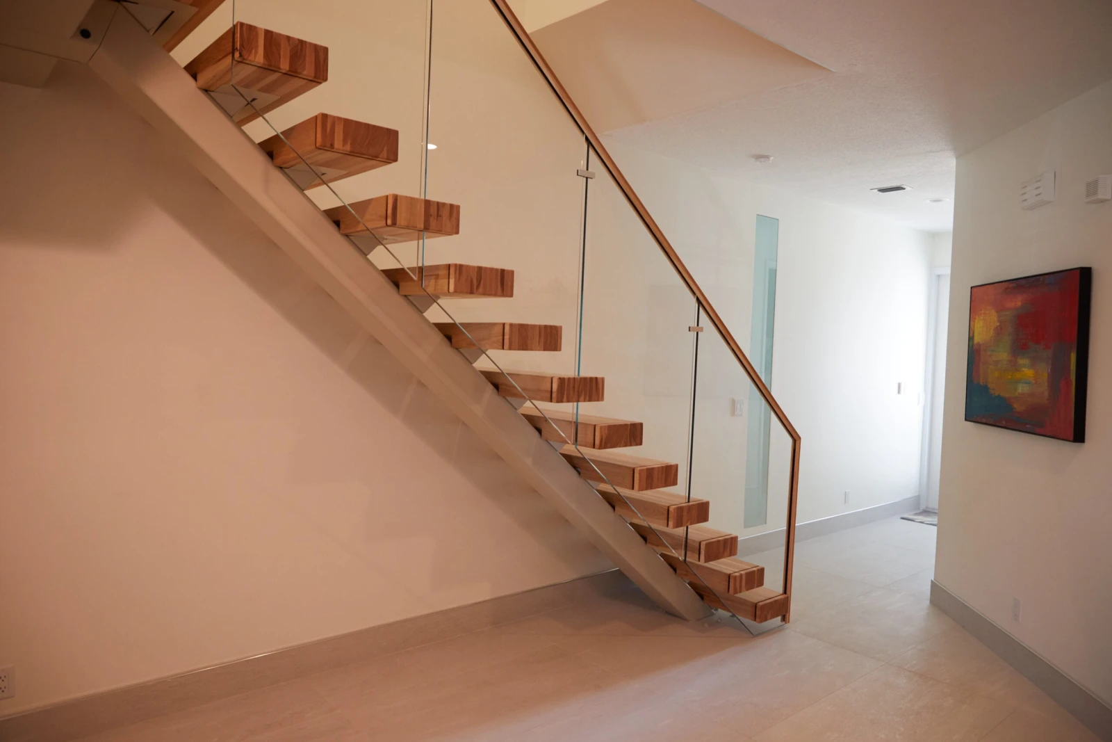 Full run of the stair in a bright hall with framed art beyond