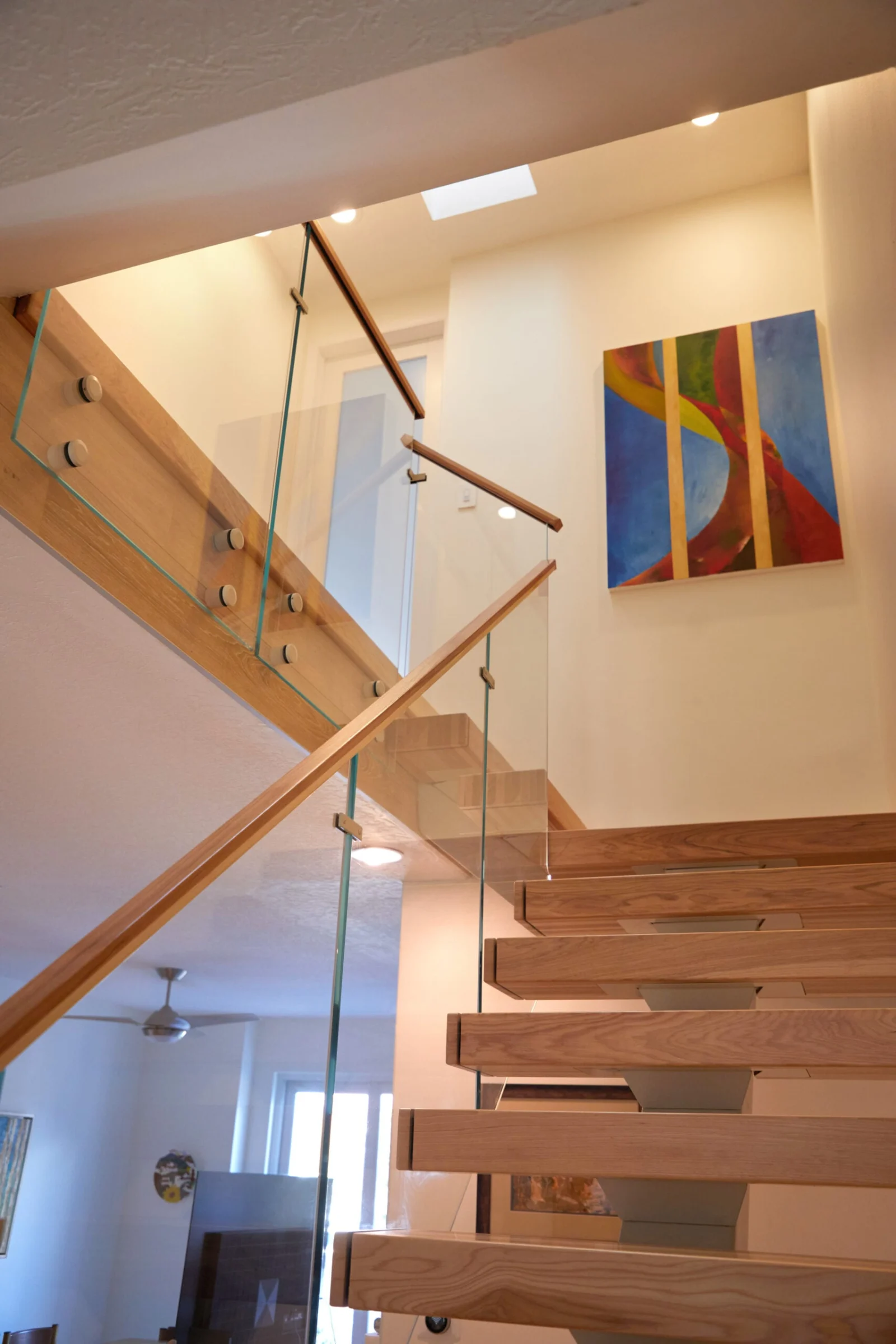 Looking up toward the landing where glass railing meets a wood handrail