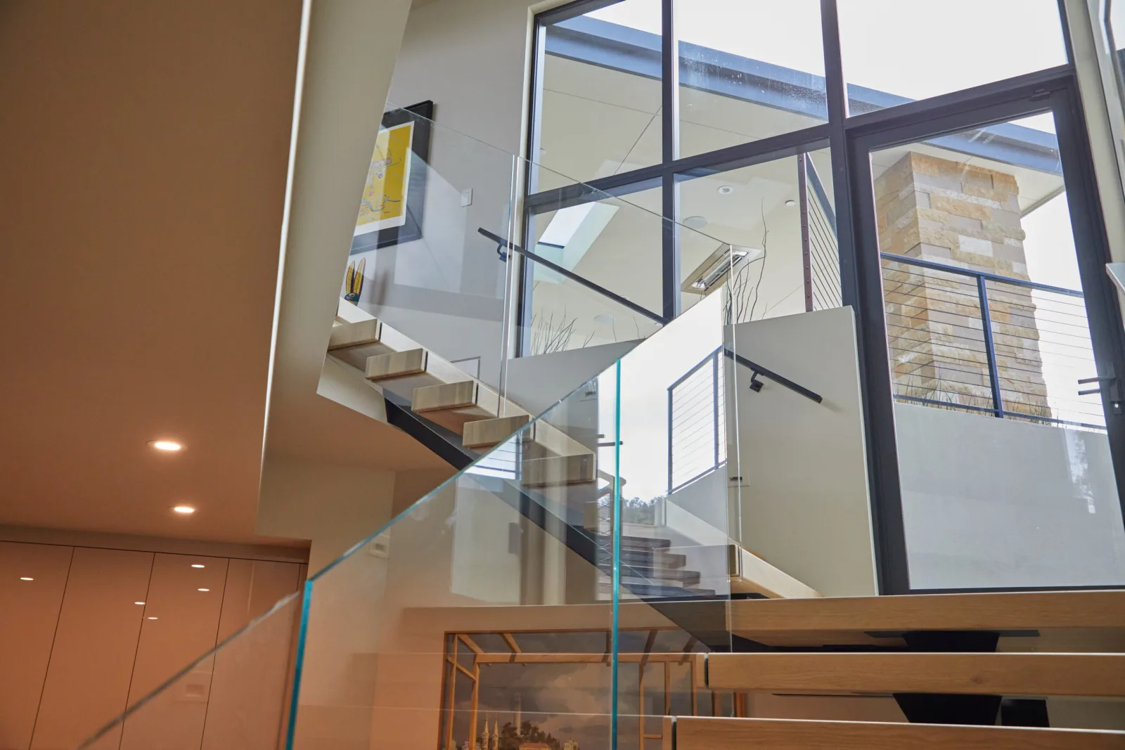 Two-story stairwell with several glass railing runs and floor-to-ceiling windows