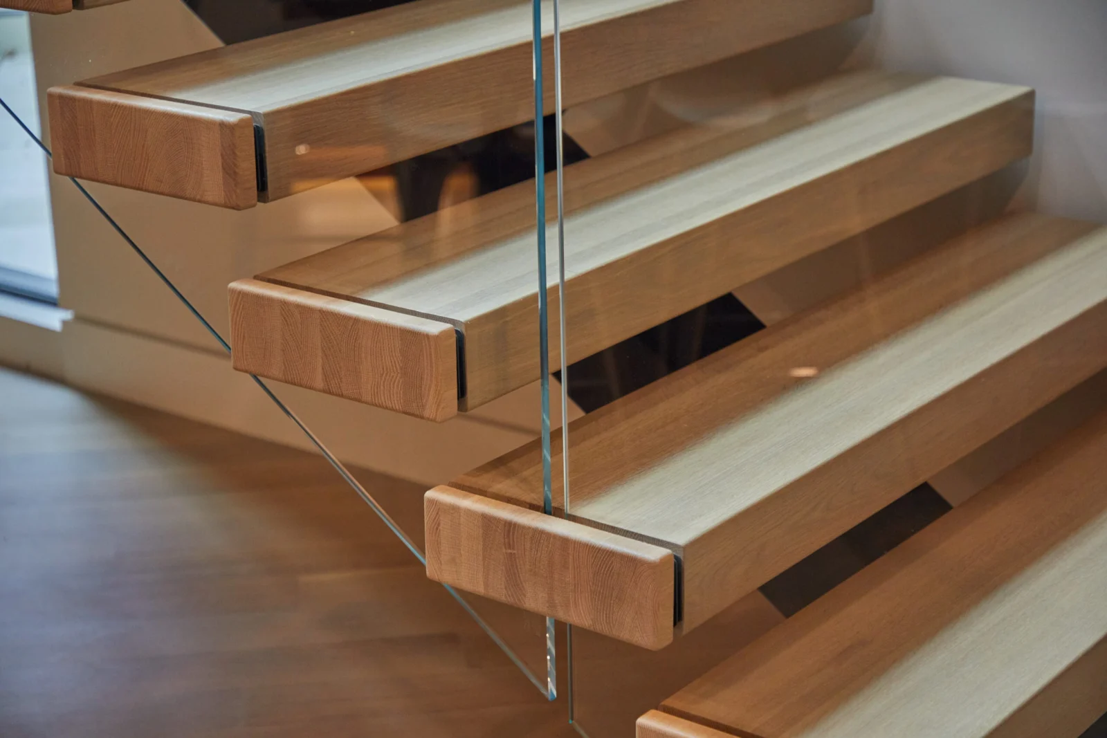 Close view of squared tread ends meeting a frameless glass panel