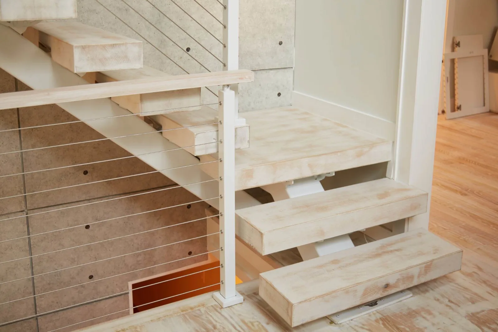 Bottom treads and white post base with cable infill beside a floor-level light