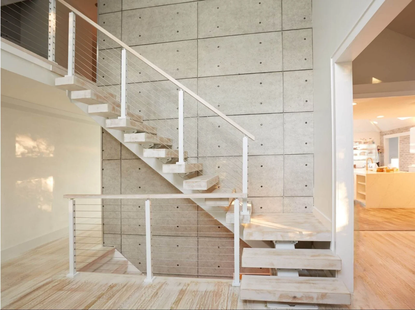 White cable railing and whitewashed treads set against a panelized concrete feature wall