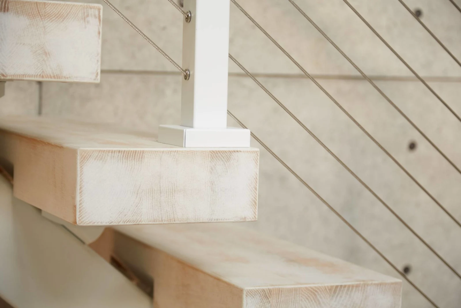 Close detail of a cantilevered tread edge and white post shoe against cable lines