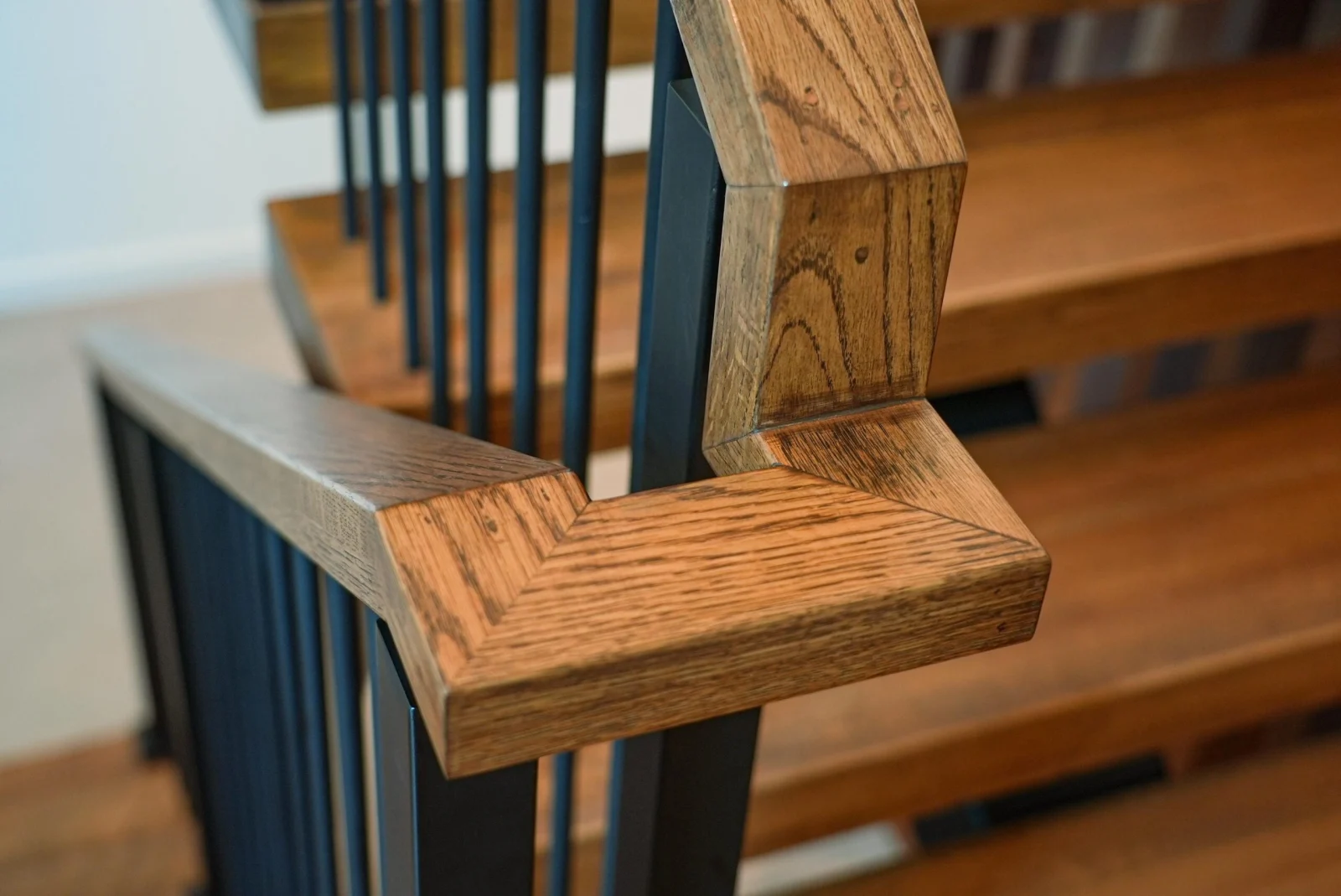 Close view of the mitered wood handrail corner above black balusters